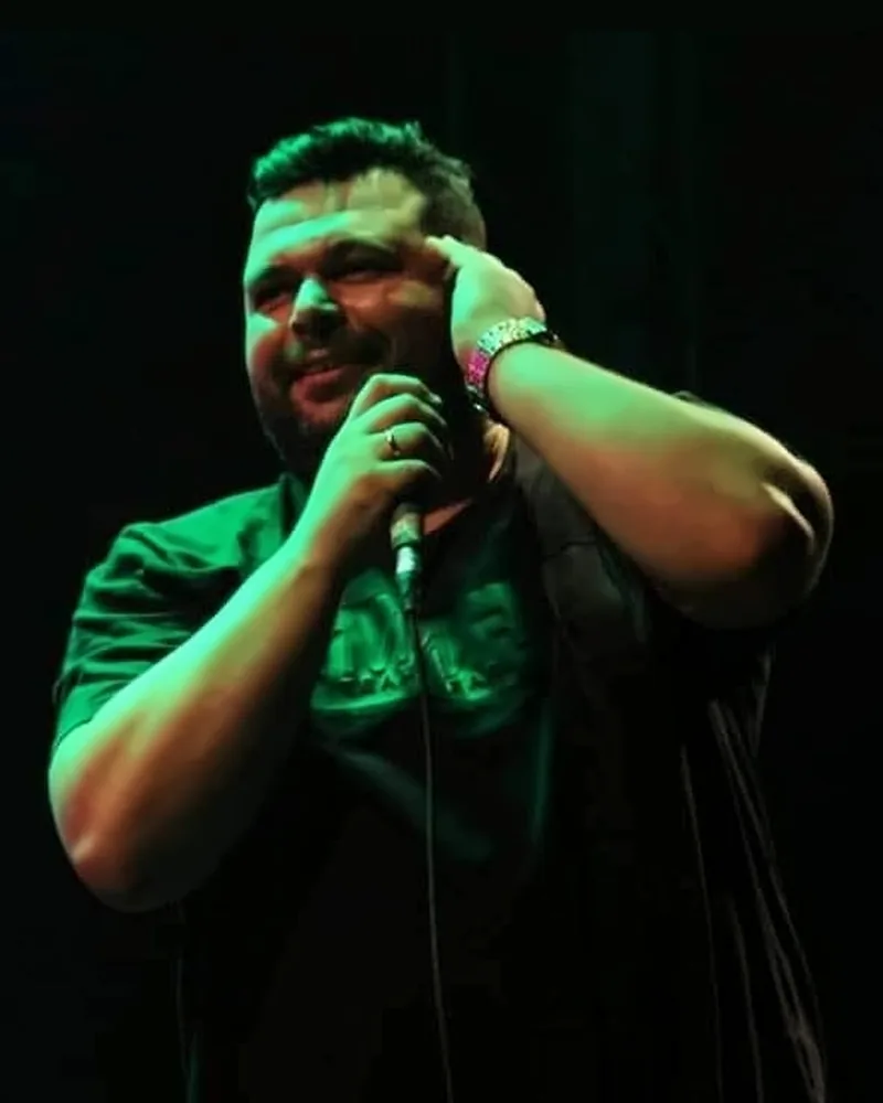 Alex Dias cantando no palco, com o microfone na mão